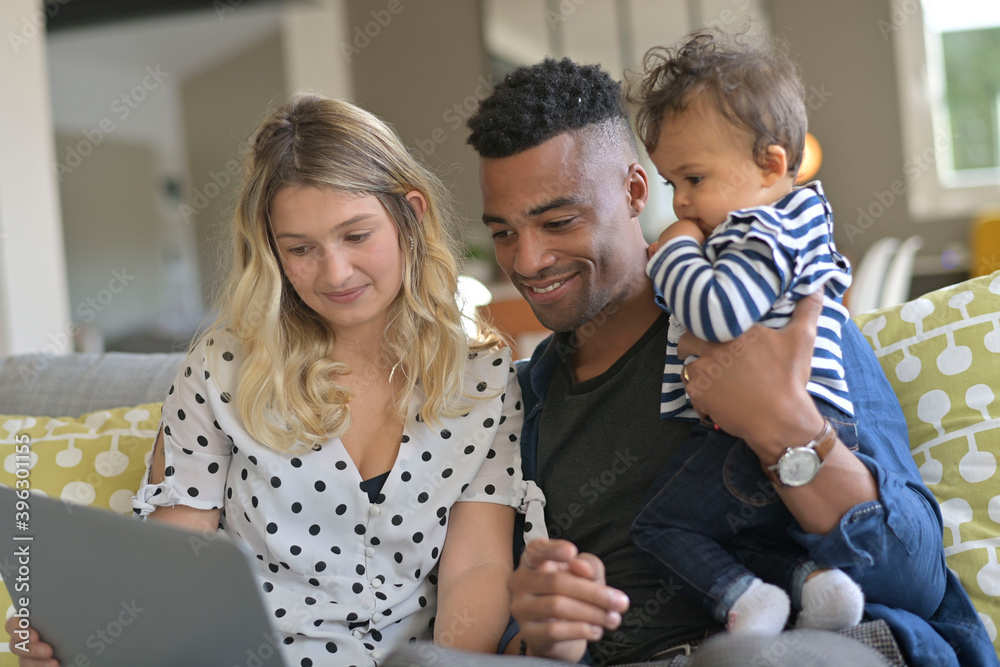 Parents with baby girl using laptop computer at home