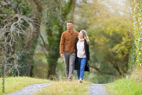 Mixed-raced couple enjoying walk in country path during autumn season