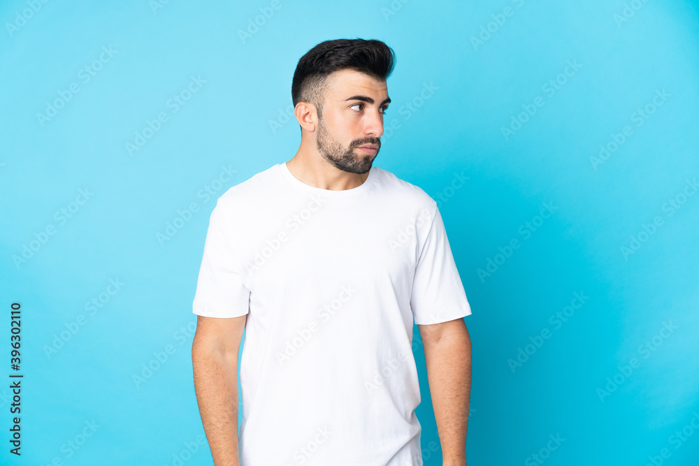 Caucasian man over isolated blue background looking to the side Caucasian man over isolated blue background looking to the side