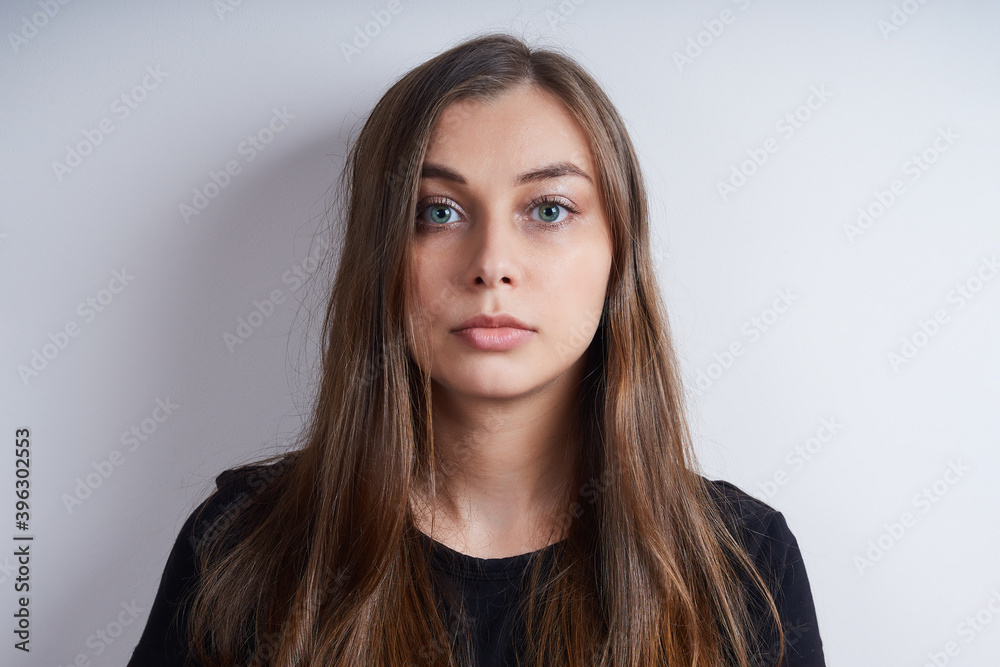 Portrait of a young serious woman in a black shirt, on a gray background. Portrait of a young serious woman in a black shirt, on a gray background.