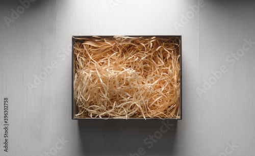 Top view of an open box with packing sawdust. Gift wrapping on the table.