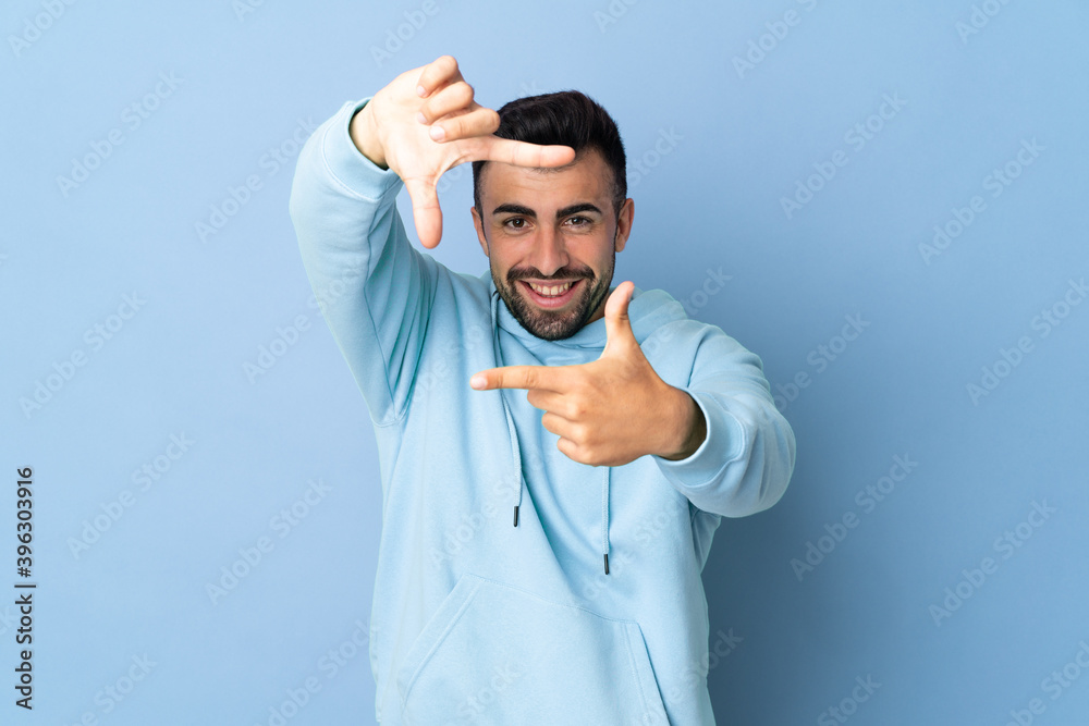 Caucasian man over isolated blue background focusing face. Framing symbol Caucasian man over isolated blue background focusing face. Framing symbol