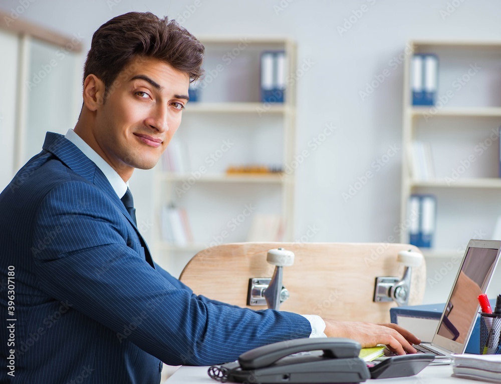 Fototapeta premium Young businessman with skate in office in sports concept