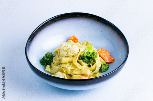 Italian pesto pasta in a blue ceramic bowl isolated on a white background close up.