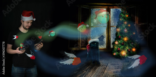 Photo post on the theme of Christmas and New Year. A young man in the image of Santa Claus with smartphones sends gifts against the background of a winter window, a black cat and a Christmas tree.