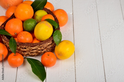 Various citrus fruits in a wicker basket on a white board