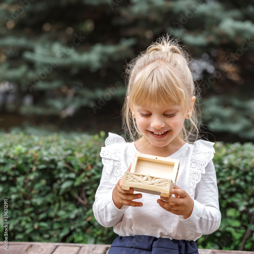 beautiful little girl looks fascinated at a wooden box.