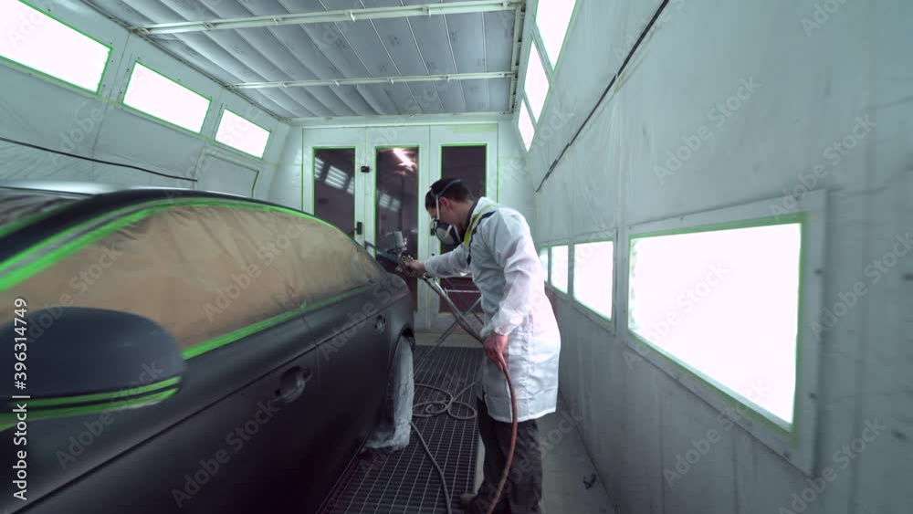 Car body painter spraying car in paint booth Car body painter spraying car in paint booth
