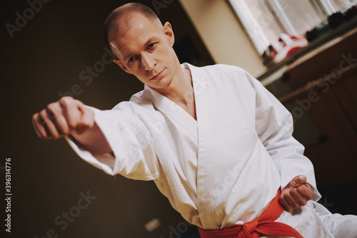 Bald man strikes while standing in karate stance. 