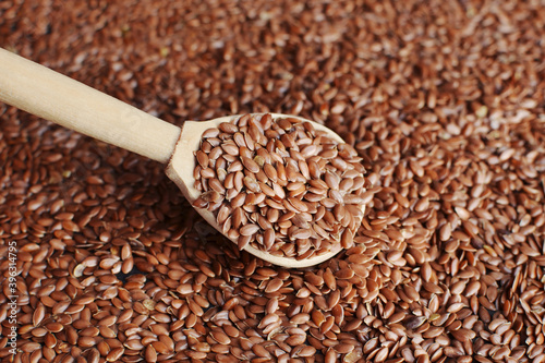 Dry uncooked flax seeds in wooden spoon.