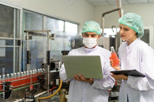 Female quality inspection hold a non-standard juice bottle. The Prince records the mistake of an ambush to keep a record of product. Processed fruit juice and production quality inspection.