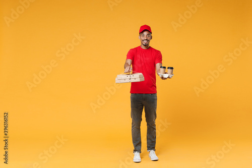 Full length delivery employee african man in red cap blank print t-shirt uniform work courier dealer service concept hold give food order pizza cardboard boxes isolated on yellow background studio