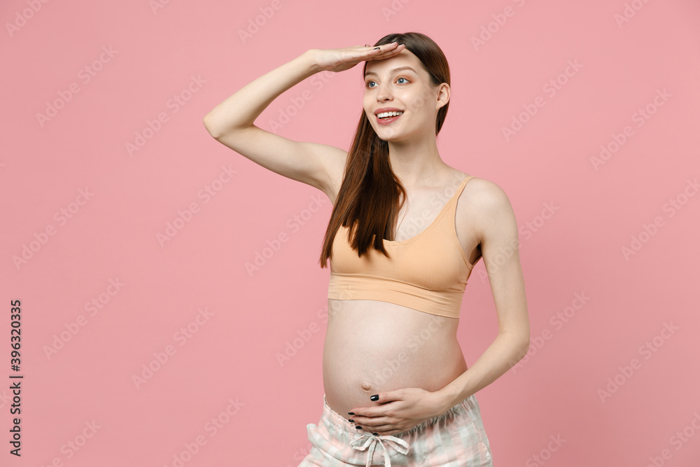 Young fun pregnant woman in basic top stroking keeping hands on big belly stomach tummy with baby look aside isolated on pastel pink background studio. Maternity family pregnancy gynecology concept. Young fun pregnant woman in basic top stroking keeping hands on big belly stomach tummy with baby look aside isolated on pastel pink background studio. Maternity family pregnancy gynecology concept.