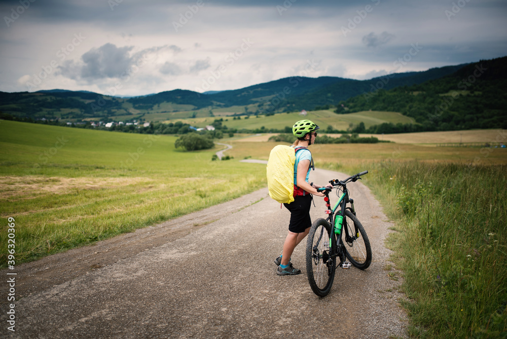 Young woman with helmet riding a bicycle. Enjoying sport in nature. 