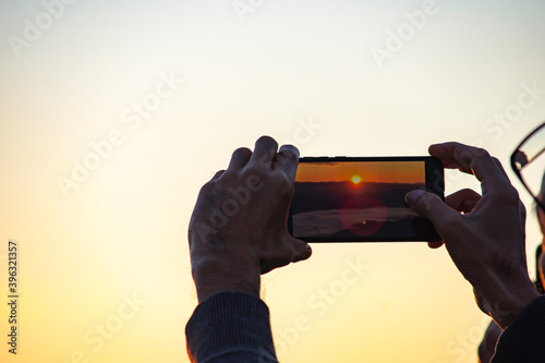 Hand holding the phone shooting the morning sun and the fog.
