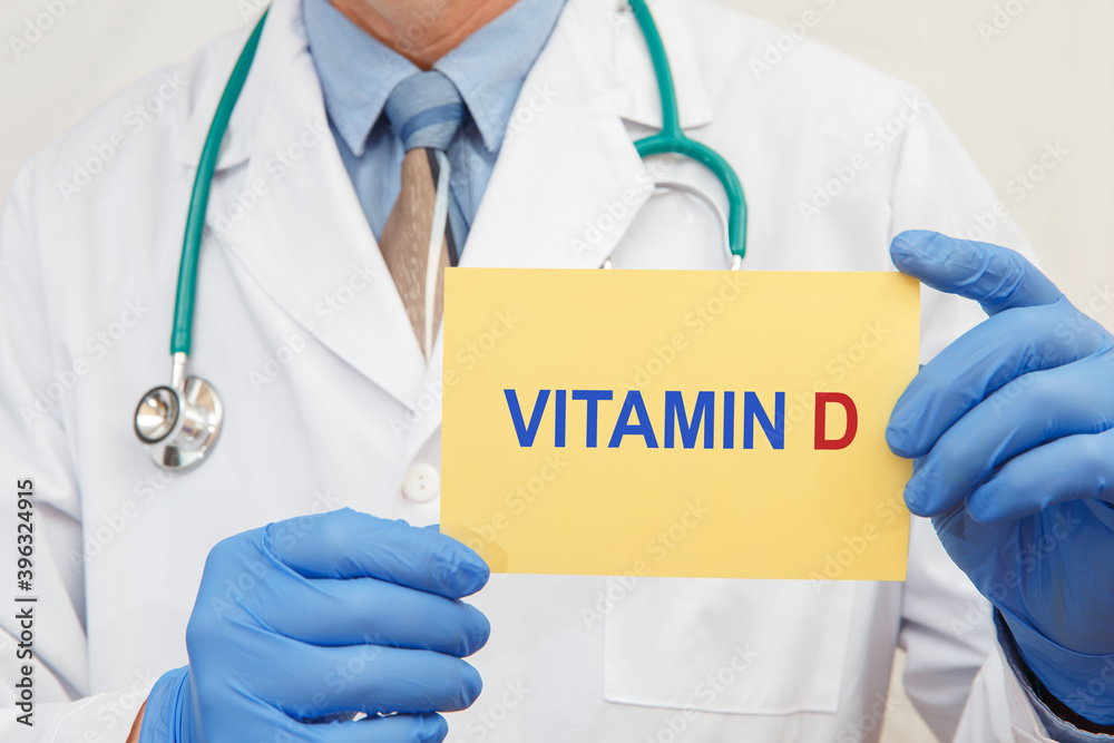 Vitamin D written on a card in doctors hands Vitamin D written on a card in doctors hands