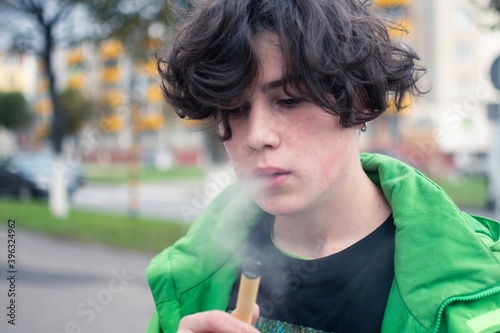 a young guy addicted to nicotine smokes an electronic cigarette. the dependence on cigarettes