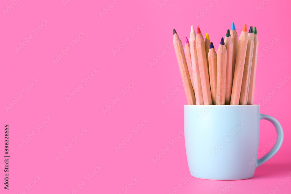 Colorful pencils in cup on pink background. Space for text Colorful pencils in cup on pink background. Space for text