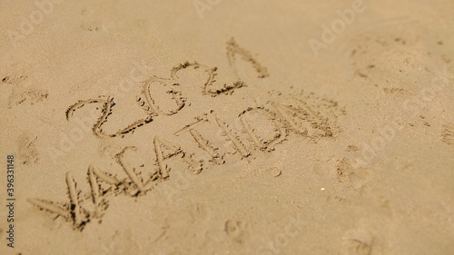 Text Vacation written in the sand of sea beach