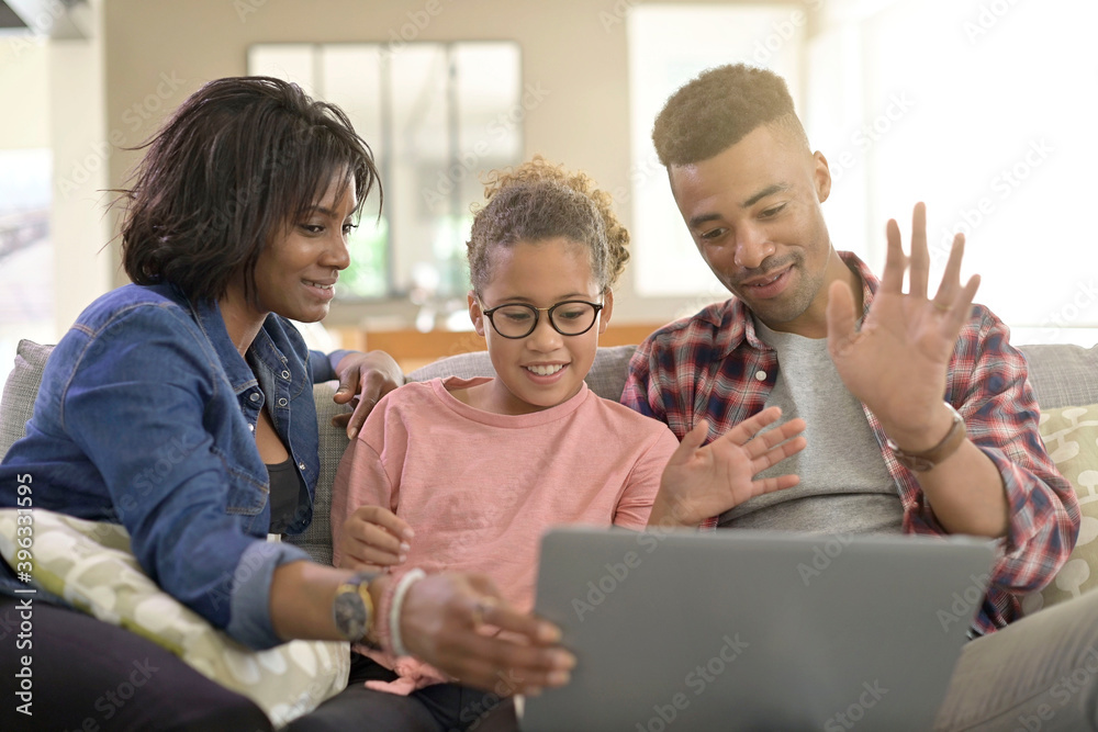 Happy family of three connected with laptop to communicate with relatives Happy family of three connected with laptop to communicate with relatives