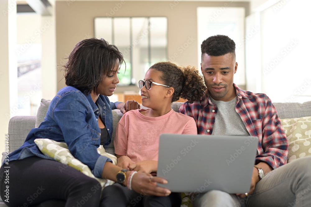 Happy family of three connected with laptop to communicate with relatives Happy family of three connected with laptop to communicate with relatives