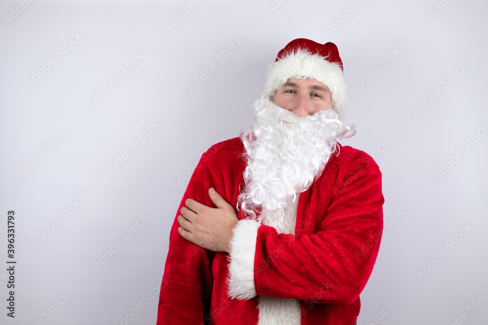 Man dressed as Santa Claus standing over isolated white background with pain on his shoulder and a painful expression Man dressed as Santa Claus standing over isolated white background with pain on his shoulder and a painful expression