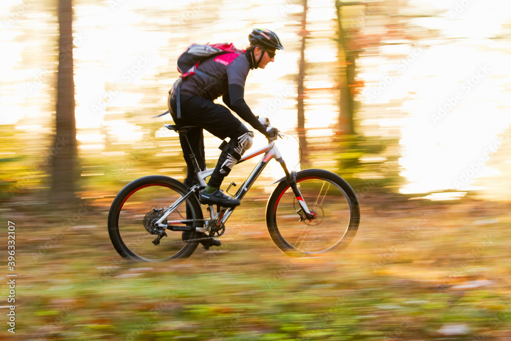 Man cycling fast with mountainbike in a forest in fall Man cycling fast with mountainbike in a forest in fall