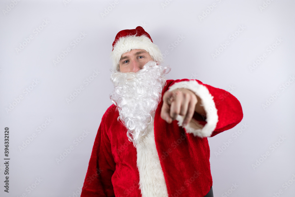 Man dressed as Santa Claus standing over isolated white background laughing at you, pointing finger to the camera with hand over body, shame expression Man dressed as Santa Claus standing over isolated white background laughing at you, pointing finger to the camera with hand over body, shame expression