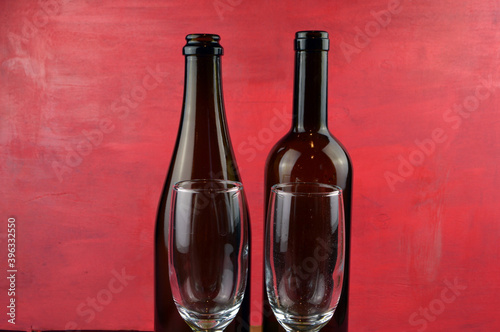 
empty glasses and bottles of wine stand on wooden background