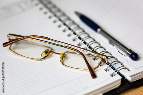 Glasses and a pen on open notebook.