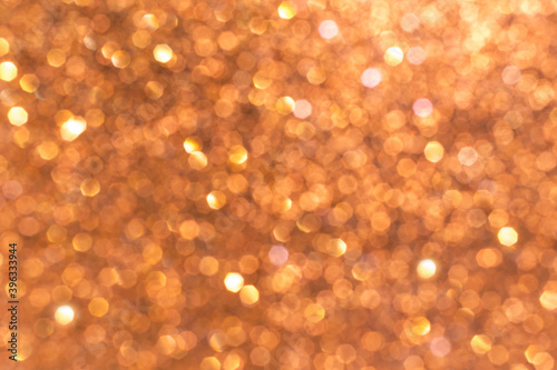 Blurry sparkling bokeh lights of golden pink and orange color, shiny festive backdrop, defocused twinkle, Christmas or New Year background