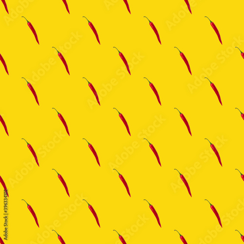 Seamless pattern made of isolated red chili peppers on yellow background. Top view. Food flatlay.