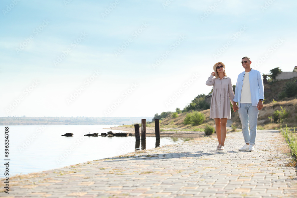 Happy couple walking along waterfront on summer day