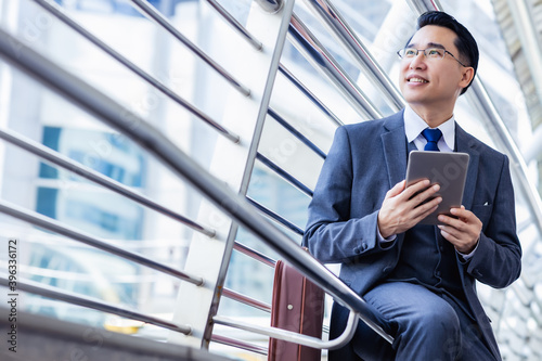 Handsome asian businessman holding digital tablet, wear suit and eyeglasses. Leadership executive business guy get successful of business. Male get confidence. Professional businessman portrait