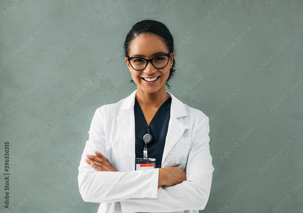 Portrait of smiling female doctor with crossed arms. Young medical specialist wearing eyeglasses and white jacket. Portrait of smiling female doctor with crossed arms. Young medical specialist wearing eyeglasses and white jacket.
