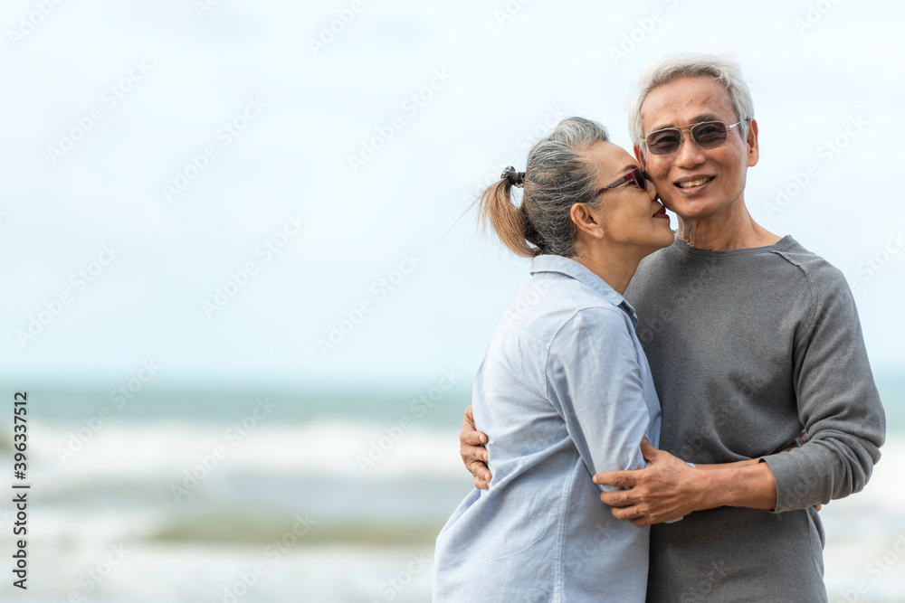 Asian Lifestyle senior couple hug and kiss on the beach happy in love romantic and relax time.  People tourism elderly family travel leisure and activity after retirement