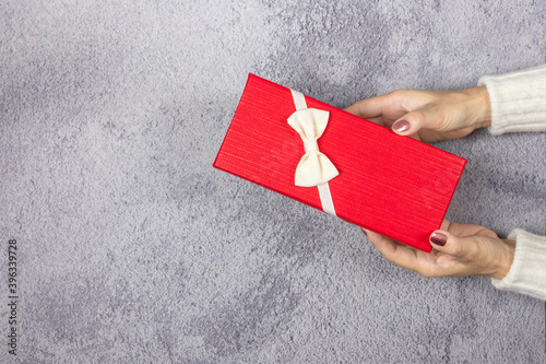 Woman's hands holding red gift box on the table.- Christmas and New Year concept. photo