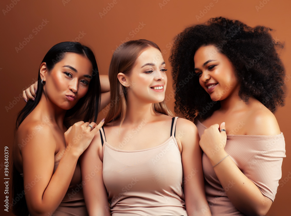 Obraz premium young pretty asian, caucasian, afro woman posing cheerful together on brown background, lifestyle diverse nationality people concept