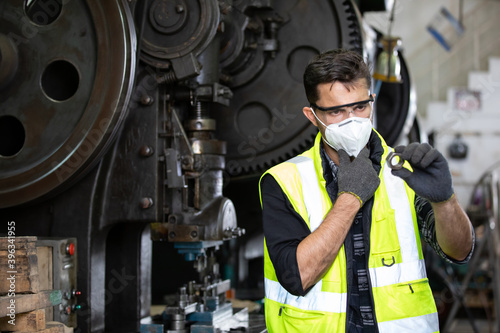 engineer man or factory worker wearing protective face mask and looking screw