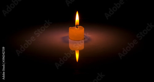 A white candle burning on a dark. 