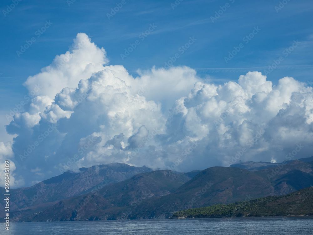 Panoramic landscape of a rocky coastline with dramatic cumulus clouds and the Mediterranean Sea, near Saint Florent, Corsica France