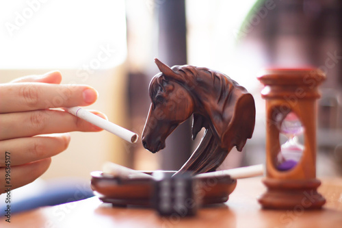 horse ashtray and hand with cigarette