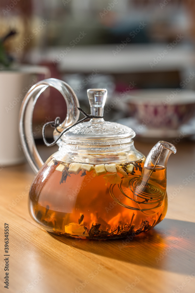 Glass transparent kettle with hot apple tea on wooden table at cafe Glass transparent kettle with hot apple tea on wooden table at cafe