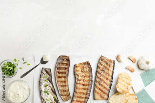 Delicious grilled eggplant slices with sauce on grey table, flat lay. Space for text