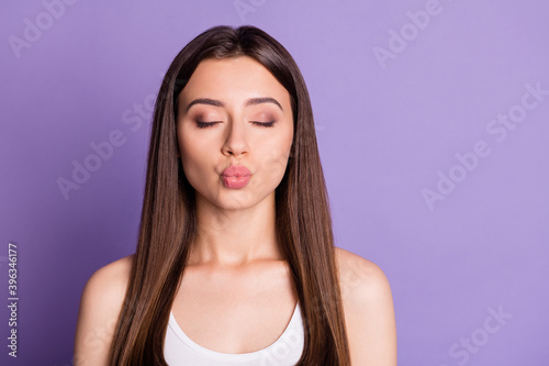 Photo portrait of woman sending air kiss with closed eyes isolated on vivid purple colored background
