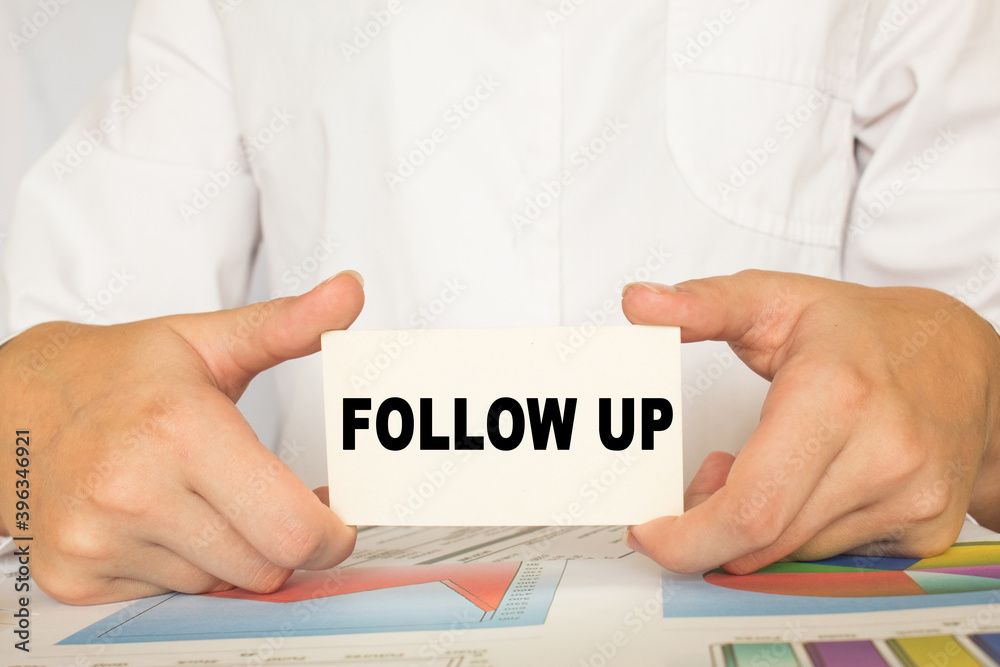 a man in the office holds a card with text FOLLOW UP. business concept a man in the office holds a card with text FOLLOW UP. business concept