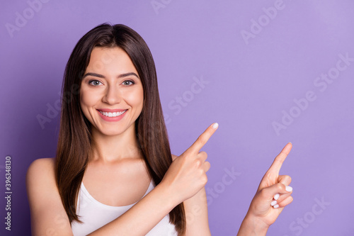 Photo of lovely sweet young lady dressed casual white clothes looking pointing two fingers empty space isolated purple color background