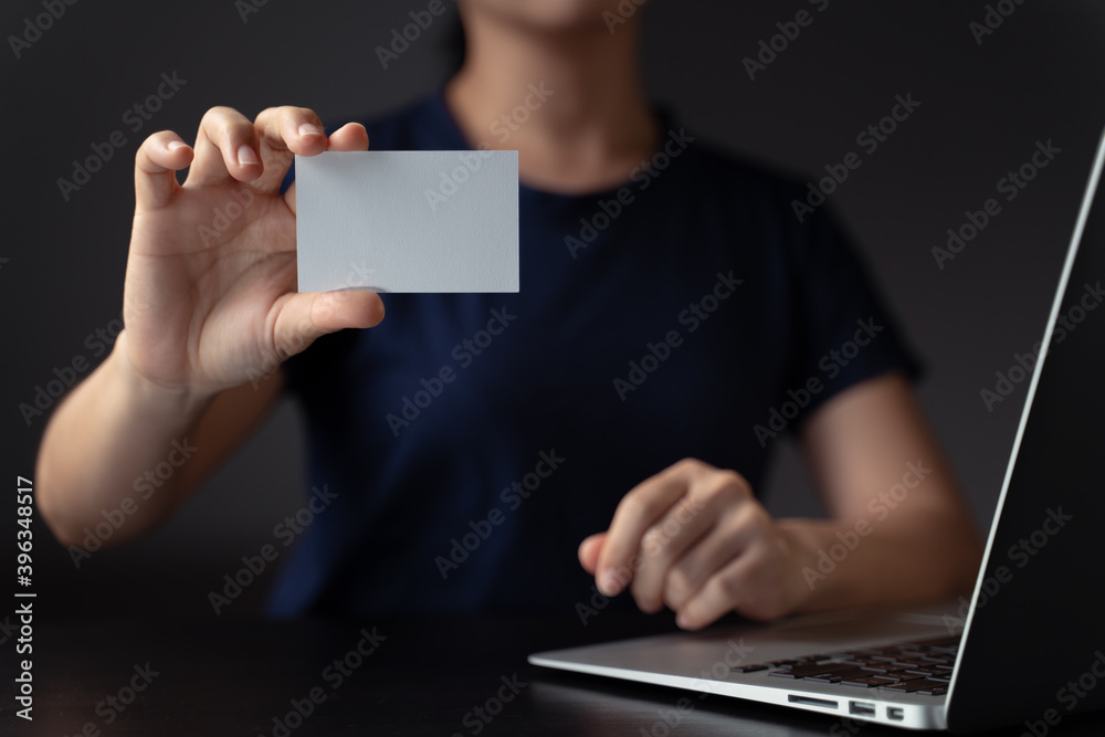 Naklejka premium Hands showing name card and working with laptop.
