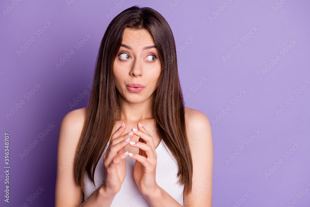 Photo of shy sweet young lady dressed casual white clothes hands together looking empty space isolated purple color background Photo of shy sweet young lady dressed casual white clothes hands together looking empty space isolated purple color background