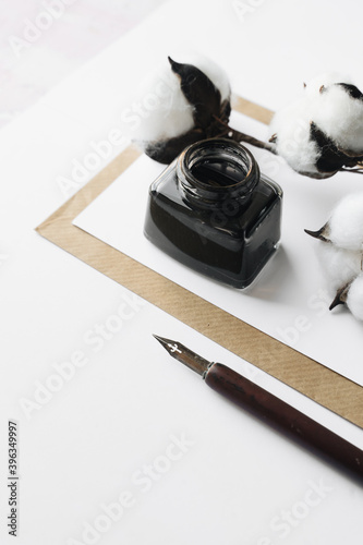 Set of vintage dip pen, inkpot and blank paper sheet with envelope on white wooden table photo